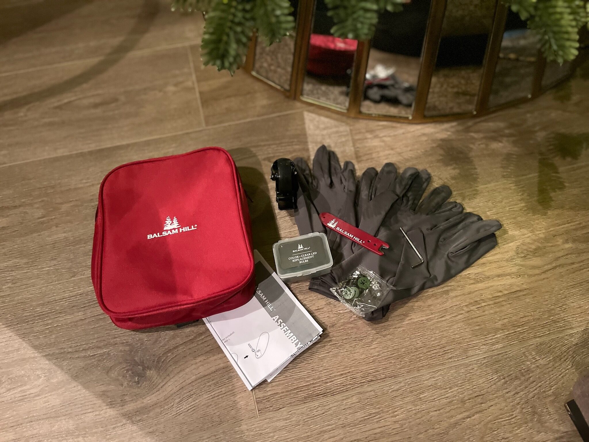 A photo of the accessories that come with a Balsam Hill Canada Flip Tree, including gloves, spare wheel, extra bulbs, instructions and assorted hardware.